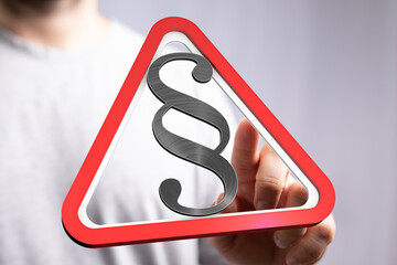 Hand points to a digital warning sign with a paragraph symbol, emphasizing legal matters.