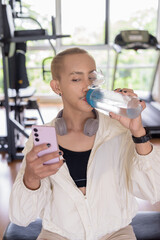 Non-binary gay man with mustache and androgynous appearance working out indoors in gym. Wearing...