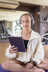 Fototapeta premium Non-binary gay man with mustache and androgynous appearance working out indoors in gym. Wearing feminine sports bra and using water bottle. Inclusive fitness concept with genderfluid representation.