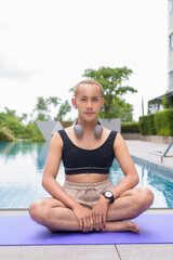 Genderfluid individual with mustache and lipstick relaxing poolside while wearing a bikini-style...