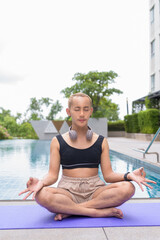 Genderfluid individual with mustache and lipstick relaxing poolside while wearing a bikini-style...