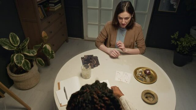 High angle shot of unrecognizable tarot reader putting cards on table letting her client choose one