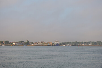 Obraz premium Yarmouth on the Isle of Wight as viewed from the sea. Showing the town, ferry and marina with yachts and sail boats.