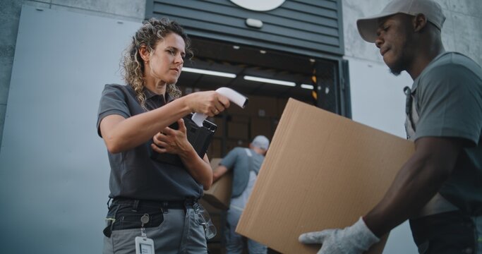 Diverse Employees Carrying Cardboard Boxes to Logistics Distribution Warehouse. Female Manager Scanning Parcels with Barcode Scanner, Using Digital Tablet. Online Orders, Delivery, E-Commerce Goods.