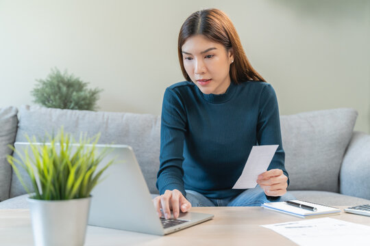 young woman looking at credit card invoice checking receipt before pay debt via mobile app at home