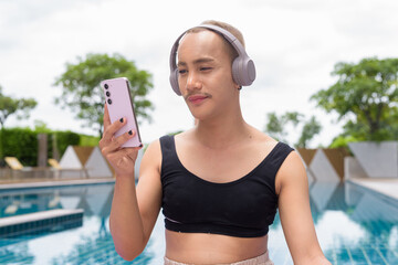 Genderfluid gay man with mustache and lipstick relaxing poolside while wearing a bikini-style top....