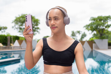 Genderfluid gay man with mustache and lipstick relaxing poolside while wearing a bikini-style top....