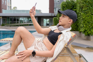 Genderfluid gay man with mustache and lipstick relaxing poolside while wearing a bikini-style top....