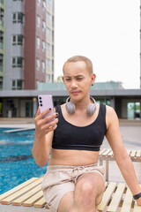 Genderfluid gay man with mustache and lipstick relaxing poolside while wearing a bikini-style top....