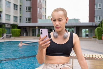 Genderfluid gay man with mustache and lipstick relaxing poolside while wearing a bikini-style top....