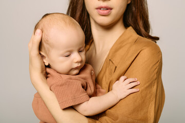 Beautiful young mother holds her baby with love and warmth in a contemporary setting
