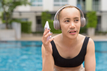Genderfluid gay man with mustache and lipstick relaxing poolside while wearing a bikini-style top....