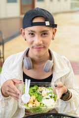 Non binary gay man eating salad