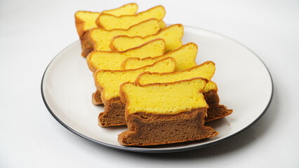 Slices of Lapis Surabaya, a traditional Indonesian layer cake, neatly arranged on a white plate. This rich and buttery cake features soft yellow and chocolate layers.