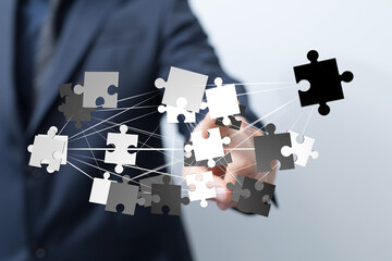 Image of a businessman connecting puzzle pieces, symbolizing teamwork, problem-solving, and...