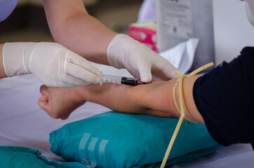 Close up nurse pricking needle syringe in the arm patient drawing blood sample for blood test , Health check