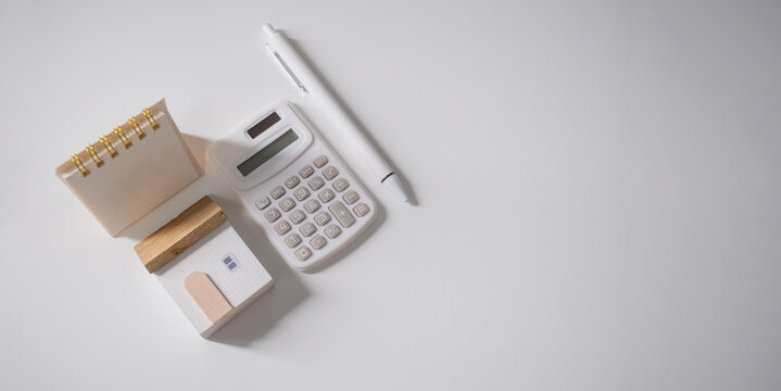 Home loan interest payment appointment. Calendar, house model, calculator and pen on the white table with copy space.