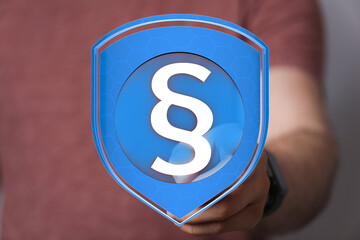 Image of a hand holding a digital shield with a paragraph symbol, representing legal protection and security.