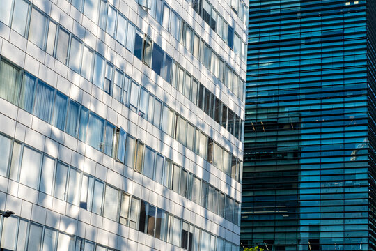 Rhythmic grids of windows and reflections create a harmonious texture of urban surfaces, weaving light and geometry into a modern facade that vibrates with life under the brightness of city daylight.