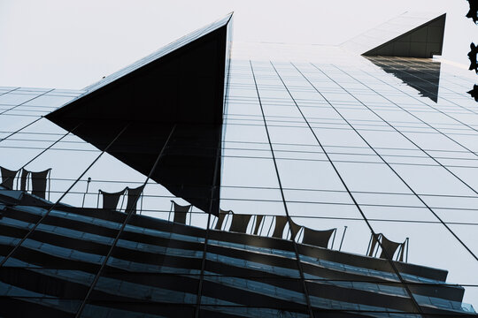 Bold triangular structures cut through the urban sky, forming abstract surfaces and dynamic shadows that bring modern architecture’s futuristic geometry into focus under vibrant daylight conditions.