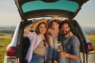 A family spends quality time outdoors, with a cheerful atmosphere as they gather by their car in a...
