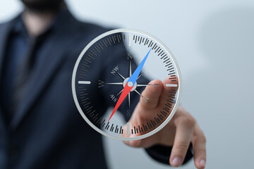 Image of a businessman using a digital compass, symbolizing strategic planning and direction. Ideal...