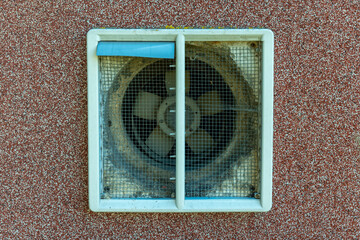 Decorative ventilation fan adds character to urban building with weathered charm in sunlight