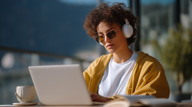 Coding in a Caf&eacute;: Young Adult with Headphones and Laptop