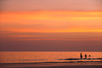 Golden hour at the seaside, where laughter meets stillness. Silhouettes of swimmers contrast...