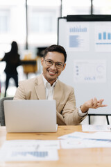 Focused Presenter with Laptop: An insightful business professional engages in a meeting, utilizing a laptop and presentation board to convey data analysis and business acumen.