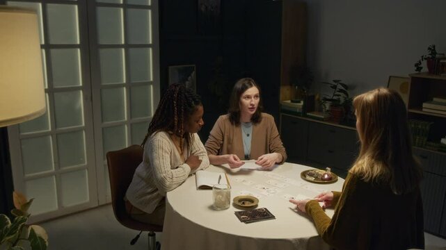 Caucasian woman showing photo of young African American man to tarot reader who holding deck of card