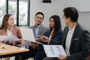 Focused Discussions: Capturing a moment of collaborative spirit, a diverse group of professionals engage in a meeting, using a laptop and documents to drive a positive outcome.