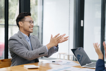 Enthusiastic Applause: A smiling man in a suit enthusiastically applauds in a business setting,...