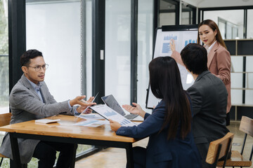 Business Collaboration Meeting: A dynamic business meeting, where professionals in formal attire collaborate around a table, animatedly discussing charts and reports in a bright, modern workspace. 