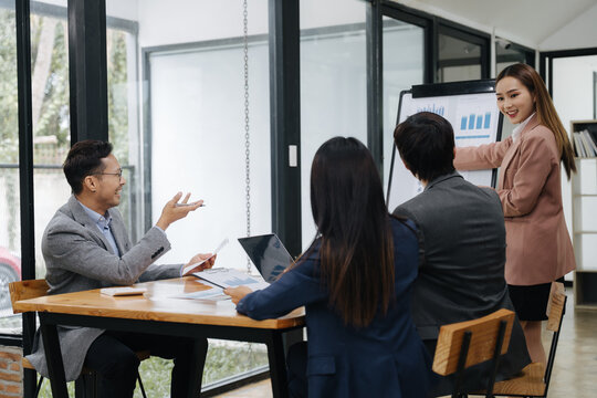 Business Collaboration in Presentation: A focused business presentation unfolds, with an elegant professional offering insights to her audience while pointing at the flip chart.