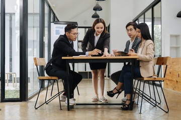 Focused Discussion: A group of business professionals collaborate, working together around a table in a bright, modern workspace, exchanging ideas and information
