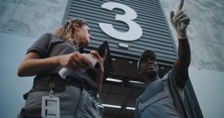 Diverse Employees Carrying Cardboard Boxes to Logistics Warehouse. Female Coordinator Scanning Parcels with Barcode Scanner, Using Digital Tablet. Online Orders and E-Commerce Goods. Low Angle Shot.