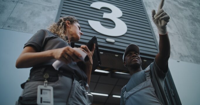 Diverse Employees Carrying Cardboard Boxes to Logistics Warehouse. Female Coordinator Scanning Parcels with Barcode Scanner, Using Digital Tablet. Online Orders and E-Commerce Goods. Low Angle Shot.