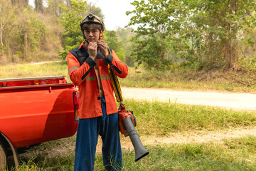 Handsome Asian male local fire fighter preparing safety gears working on duty to fight with forest...