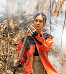 Asian female local fire fighter using tool fighting with forest fire 
