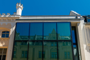 Modern architectural fusion captures reflections of historic charm in urban landscape on a sunny day