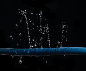 Water leaking on rubber water hose on dark background