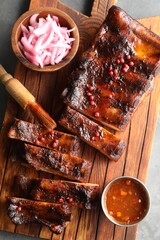 Delicious spare ribs, onion and sauce on grey table, top view