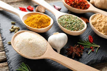 Different aromatic spices in spoons on wooden table, closeup