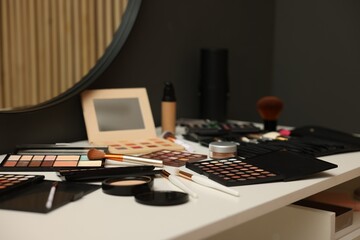 Different makeup products and brushes on dressing table indoors, closeup
