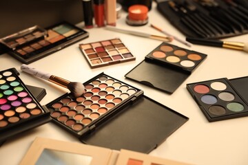 Different makeup products and brushes on dressing table, closeup