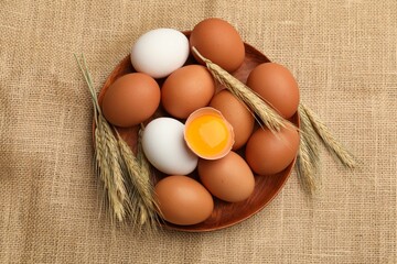 Fresh eggs and spikes on burlap cloth, flat lay
