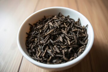 White bowl filled with dark pointed seeds resting on a wood surface