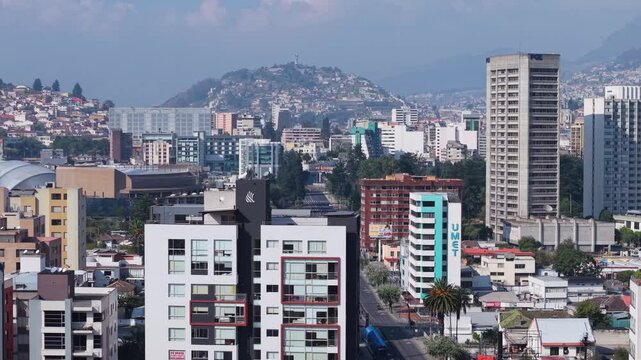 Vibrant cityscape of Quito including Corporacion Financiera Nacional building and El Panecillo hill, architectural contrasts beneath sweeping Andean mountain range