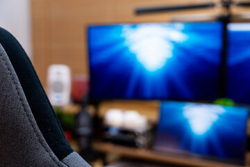 A detailed view of a modern and organized workspace, showcasing dual monitors displaying dynamic blue visuals, complemented by indoor plants and a collection of mechanical keyboards.